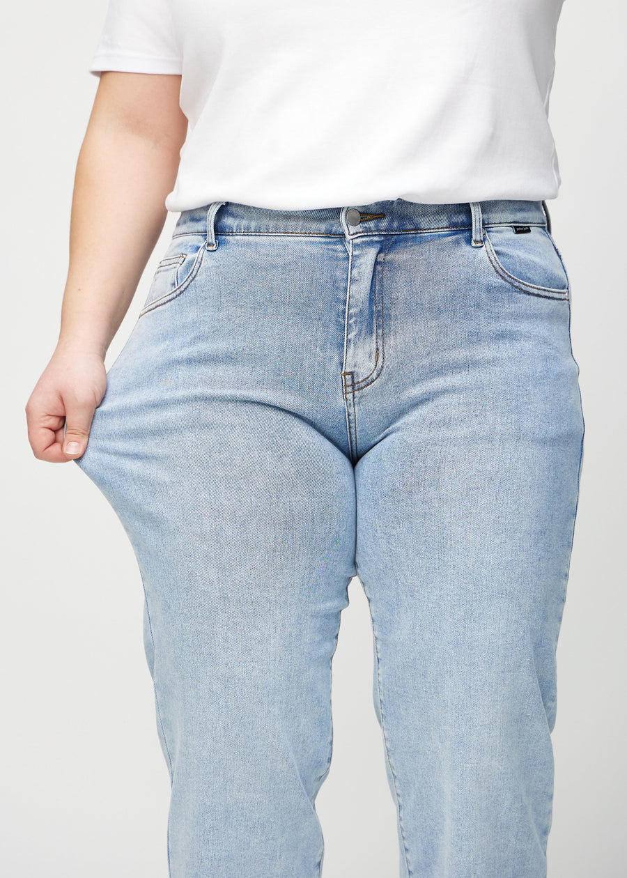 Loose-Jeans für Damen in Hellblau, Farbe Waves. Ein Plus-Size-Model dehnt den Jeansstoff am Oberschenkel, um den Stretch zu zeigen.