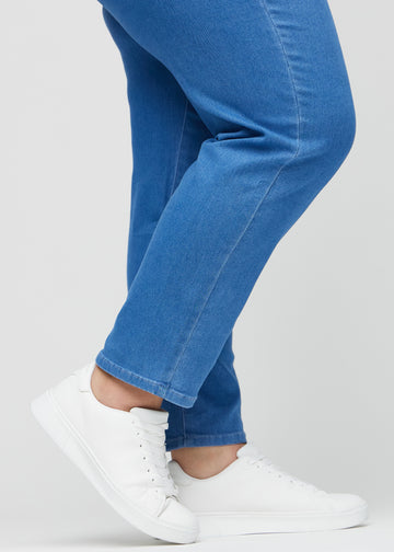 Regular-Jeans für Damen in Blau, Farbe Geraniums. Nahaufnahme an den Knöcheln eines Plus-Size-Models, um den geraden Beinabschluss zu zeigen.