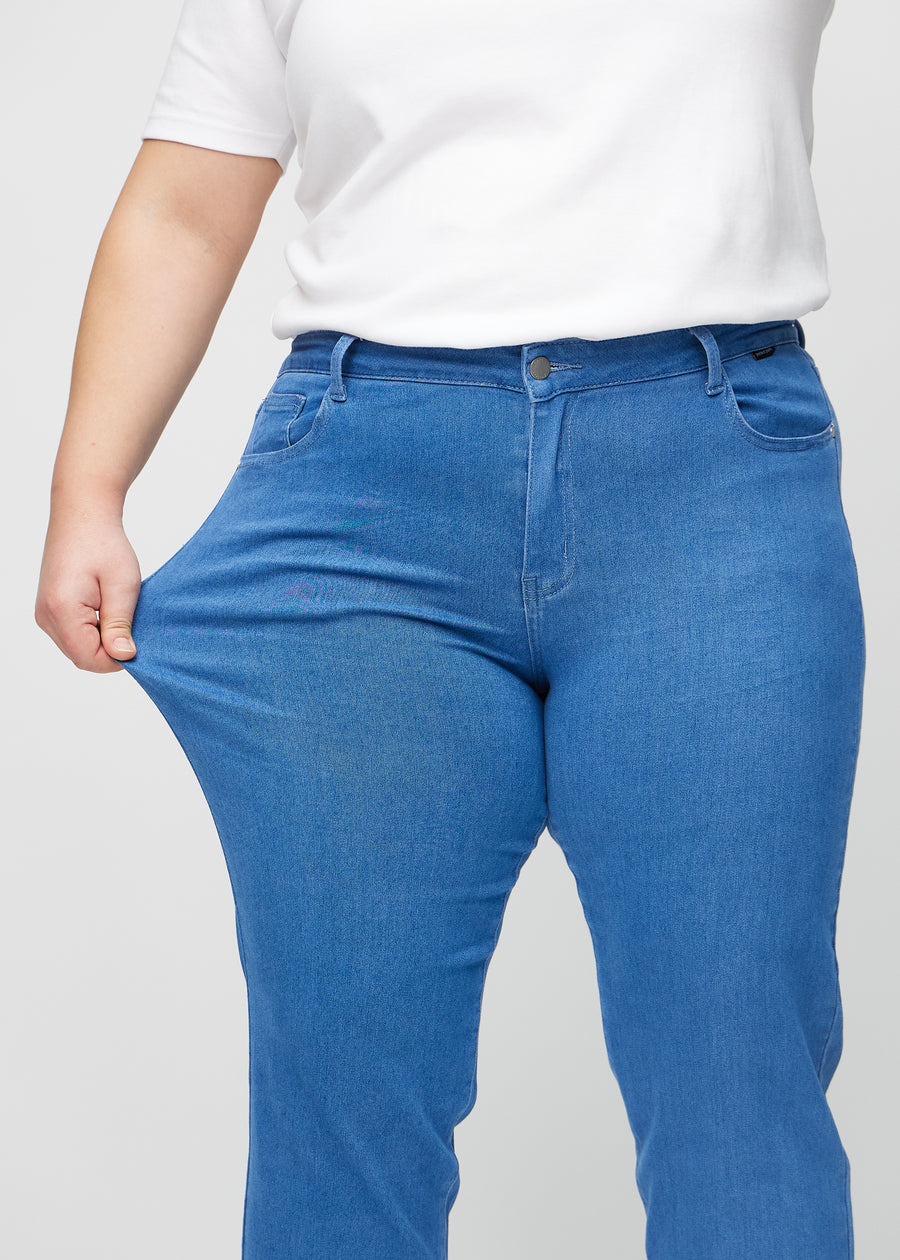 Regular-Jeans für Damen in Blau, Farbe Geraniums. Ein Plus-Size-Model dehnt den Stoff am Oberschenkel, um den Stretch zu zeigen.