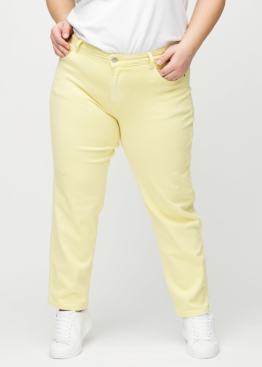 Hellgelbe regular jeans, Modellname Lemonades, die gerade am Bein herunterfallen, an einem Plus-Size-Model von vorne gesehen.