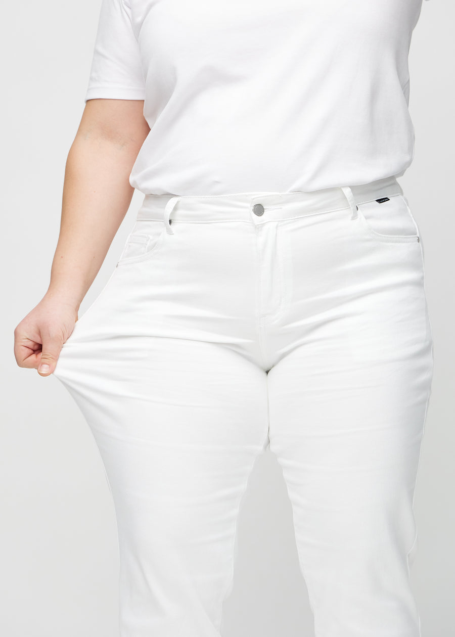 Regular-Jeans für Damen in Weiß, Farbe Marguerites. Ein Plus-Size-Model dehnt den Stoff am Oberschenkel, um den Stretch zu zeigen.
