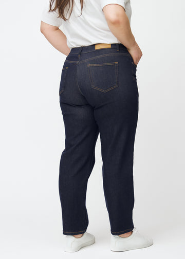 Tief dunkelblaue Denim jeans für Damen in der Farbe Midnights, von hinten an einem Plus-Size-Model gezeigt.
