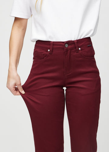 Regular-Jeans für Damen in Dunkelrot, Farbe Santas. Ein Model dehnt den Stoff am Oberschenkel, um den Stretch zu zeigen.