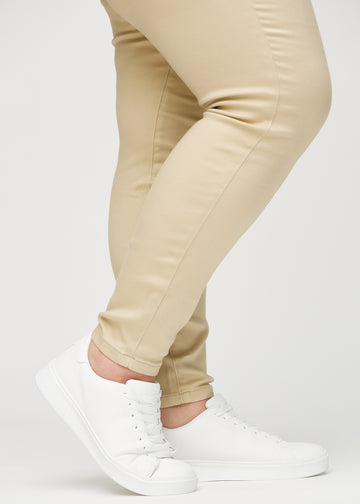 Skinny-Jeans für Damen in Beige, Farbe Gazelles. Nahaufnahme am Knöchel eines Plus-Size-Models, die eng anliegenden Beinabschlüsse sind zu sehen.