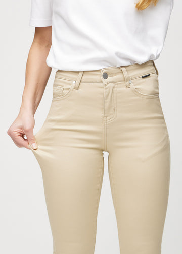Skinny-Jeans für Damen in Beige, Farbe Gazelles. Ein Model zieht am Jeansstoff am Oberschenkel, um den Stretch zu zeigen.