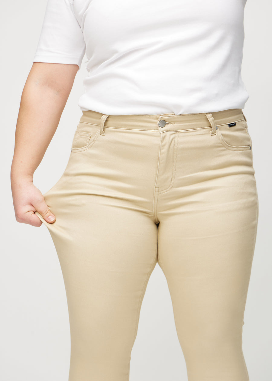 Skinny-Jeans für Damen in Beige, Farbe Gazelles. Ein Plus-Size-Model zieht am Jeansstoff am Oberschenkel, um den Stretch zu zeigen.