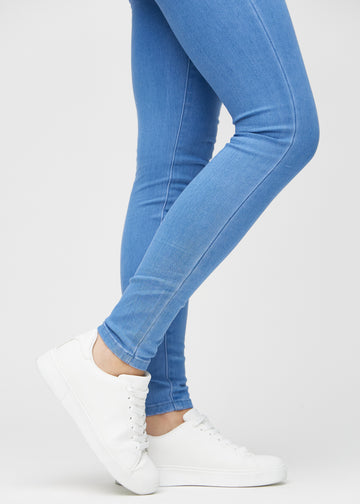 Skinny-Jeans für Damen in Blau, Farbe Geraniums. Nahaufnahme am Knöchel eines Models, die eng anliegenden Beinabschlüsse sind zu sehen.