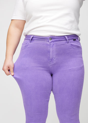 Skinny-Jeans für Damen in Lila, Farbe Lavenders. Ein Plus-Size-Model dehnt den Jeansstoff am Oberschenkel, um den Stretch zu zeigen.