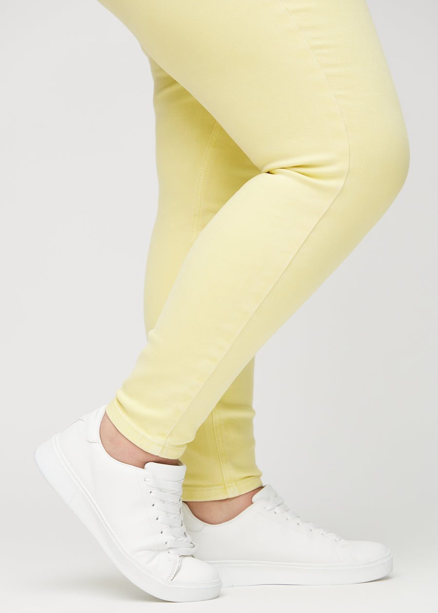 Skinny-Jeans für Damen in Hellgelb, Farbe Lemonades. Nahaufnahme der eng anliegenden Beinabschlüsse am Knöchel eines Plus-Size-Models.