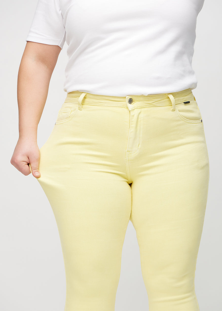 Skinny-Jeans für Damen in Hellgelb, Farbe Lemonades. Ein Plus-Size-Model dehnt den Jeansstoff am Oberschenkel, um den Stretch zu zeigen.