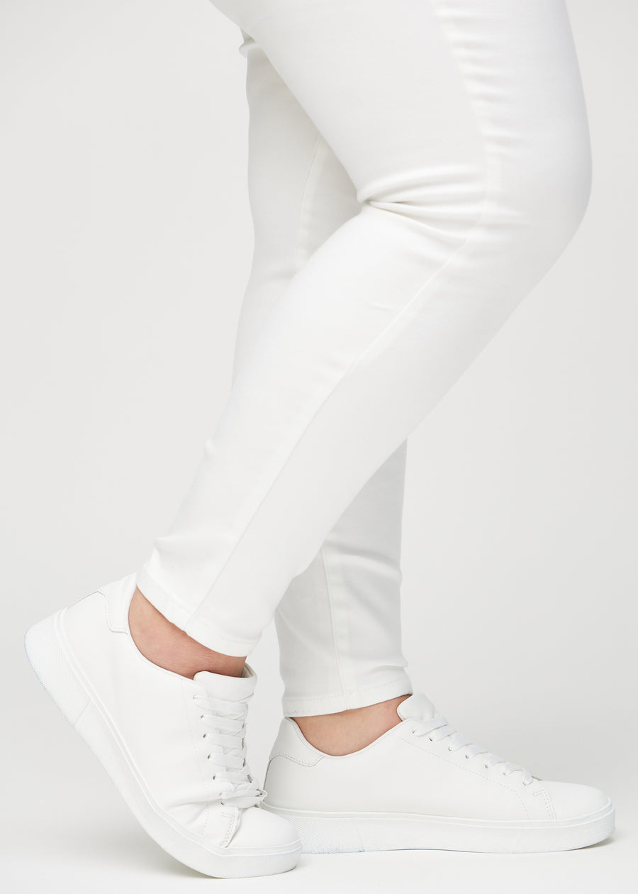 Skinny-Jeans für Damen in Weiß, Farbe Marguerites. Nahaufnahme der eng anliegenden Beinabschlüsse am Knöchel eines Plus-Size-Models.