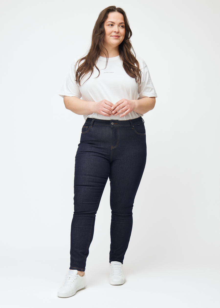 Ganzkörperbild eines Plus-Size-Models in tief dunkelblauer Denim jeans für Damen in der Farbe Midnights mit skinny Passform.