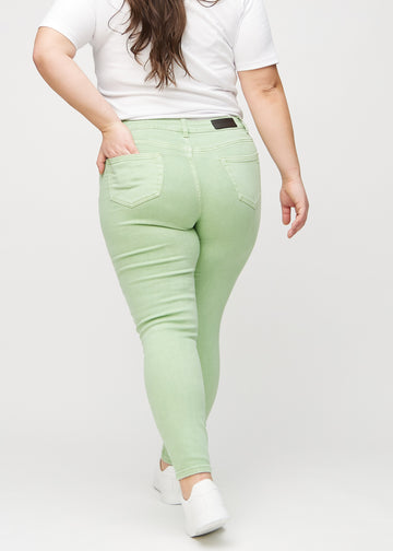 Hellgrüne skinny jeans von hinten an einem Plus-Size-Model gesehen, damit man das gesamte Produkt sehen kann.