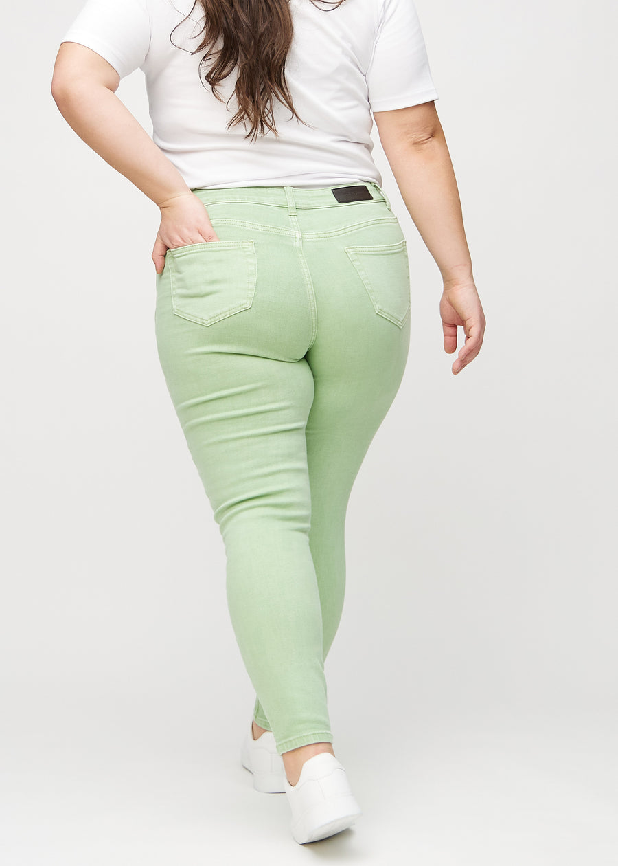 Hellgrüne skinny jeans von hinten an einem Plus-Size-Model gesehen, damit man das gesamte Produkt sehen kann.