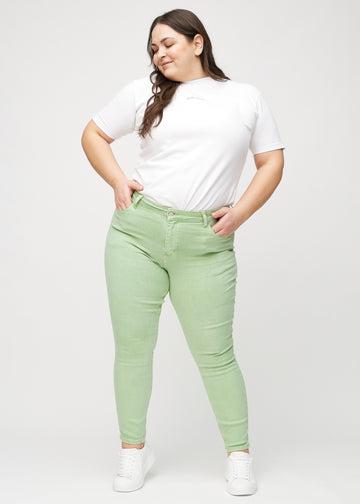 Ganzkörperbild eines Plus-Size-Models in hellgrünen skinny jeans.