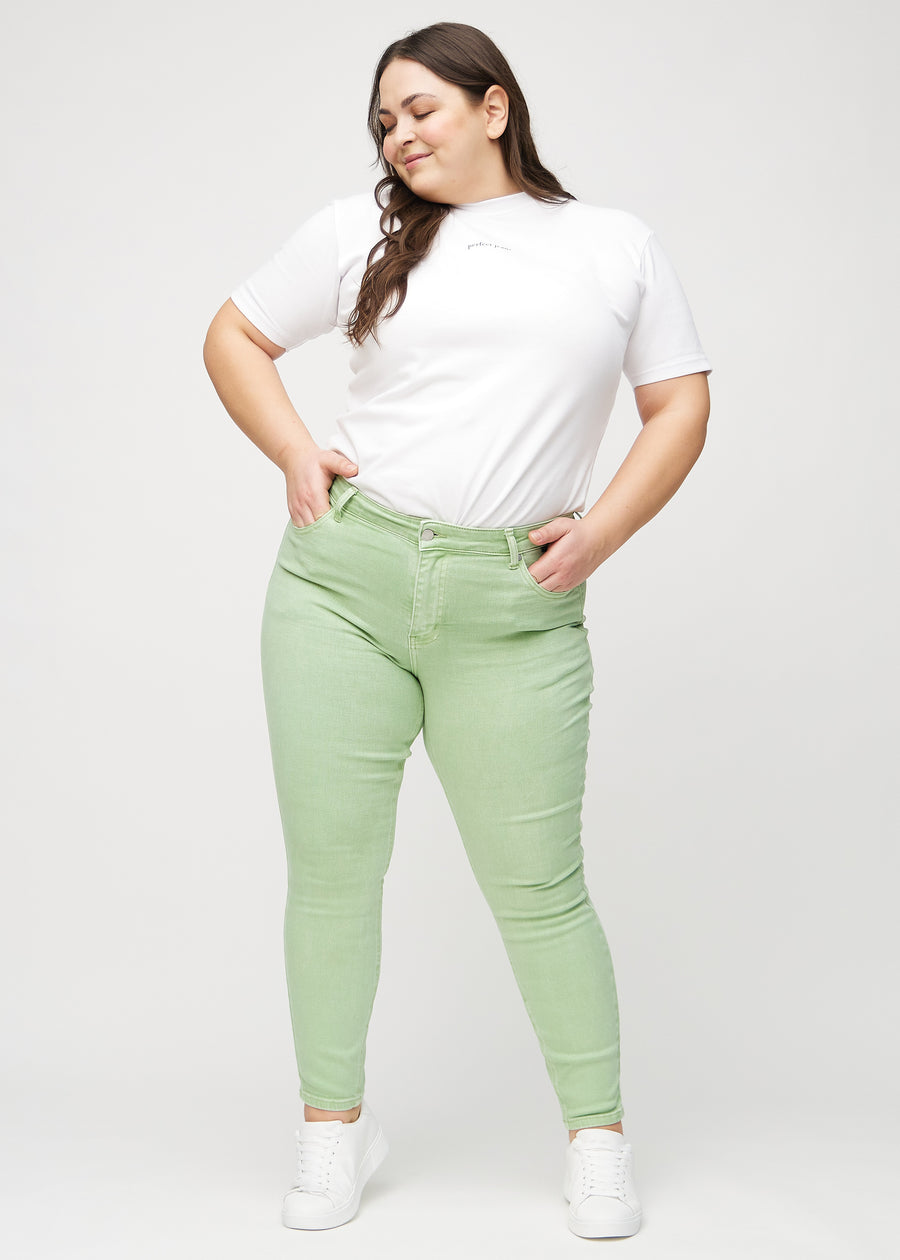 Ganzkörperbild eines Plus-Size-Models in hellgrünen skinny jeans.