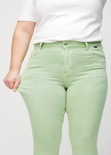 Das Plus-Size-Model zieht die Jeans am Oberschenkel auseinander, um den Stretch zu zeigen.