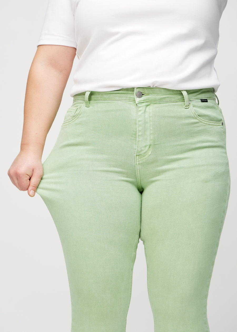 Das Plus-Size-Model zieht die Jeans am Oberschenkel auseinander, um den Stretch zu zeigen.