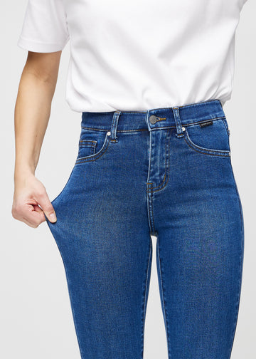 Skinny-Jeans für Damen in Dunkelblau, Farbe Oceans. Ein Model dehnt den Jeansstoff am Oberschenkel, um den Stretch zu zeigen.