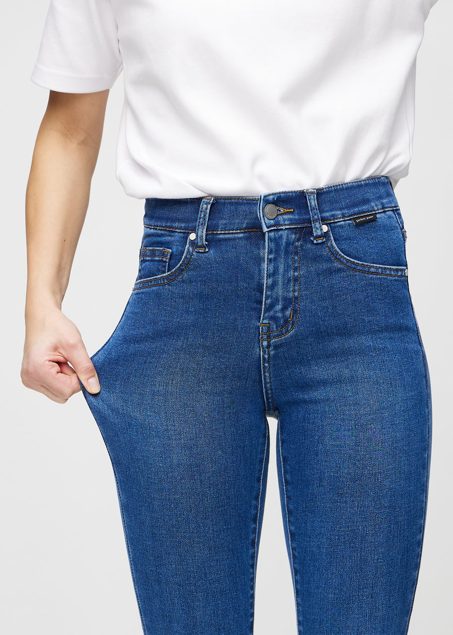 Skinny-Jeans für Damen in Dunkelblau, Farbe Oceans. Ein Model dehnt den Jeansstoff am Oberschenkel, um den Stretch zu zeigen.