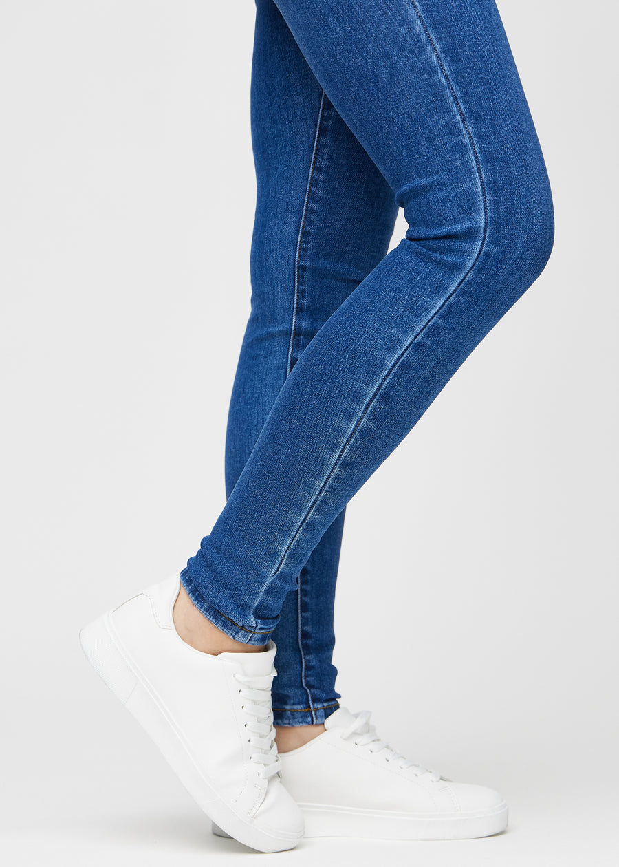 Skinny-Jeans für Damen in Dunkelblau, Farbe Oceans. Nahaufnahme der eng anliegenden Beinabschlüsse am Knöchel eines Models.