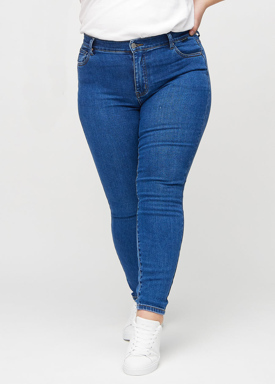 Skinny-Jeans für Damen in Dunkelblau, Farbe Oceans. Vorderansicht an einem Plus-Size-Model, mit eng anliegenden Beinen.