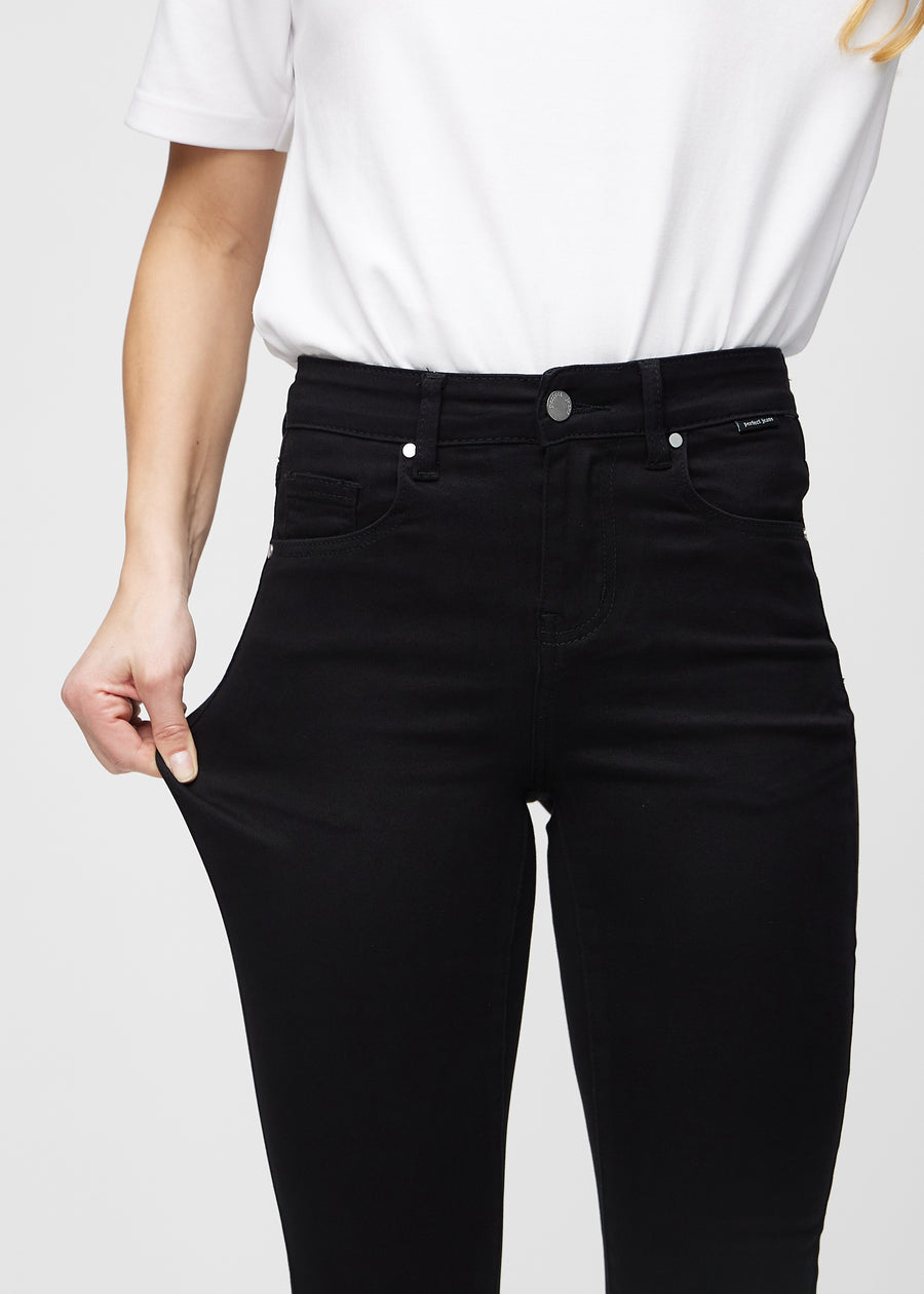 Skinny-Jeans für Damen in Schwarz, Farbe Ravens. Ein Model zieht am Jeansstoff am Oberschenkel, um den Stretch zu zeigen.