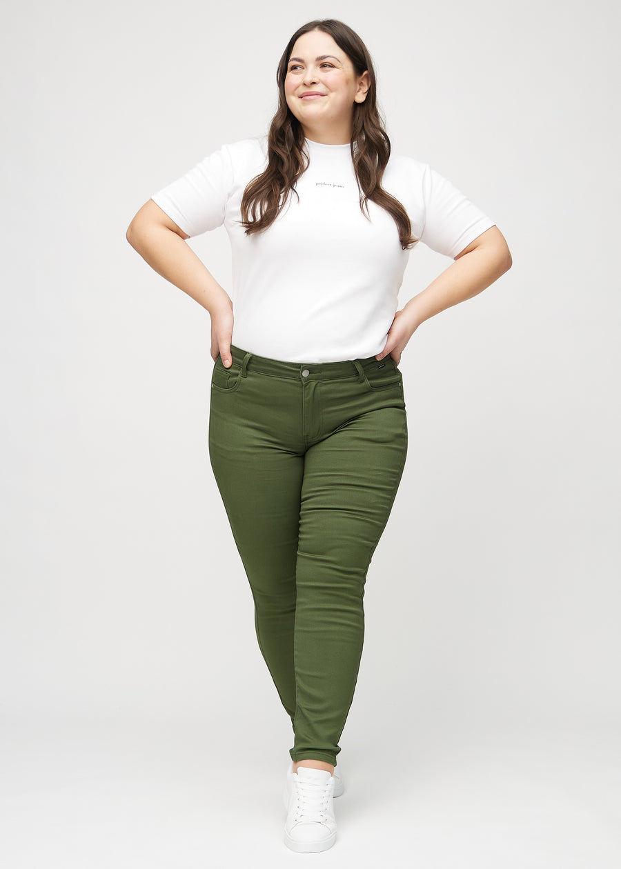 Ganzkörperbild eines Plus-Size-Models in dunkelgrünen skinny jeans.