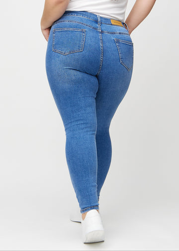 Denim skinny jeans von hinten an einem Plus-Size-Model gesehen, damit man das gesamte Produkt sehen kann.