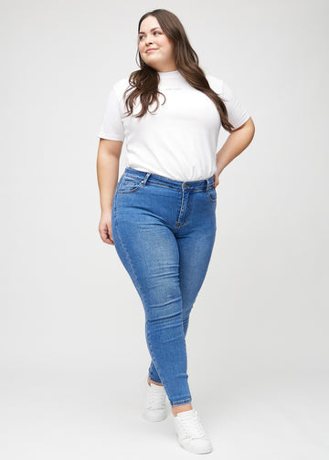 Ganzkörperbild eines Plus-Size-Models in Denim skinny jeans.