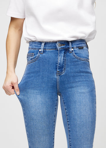 Das Model zieht die Jeans am Oberschenkel auseinander, um den Stretch zu zeigen.
