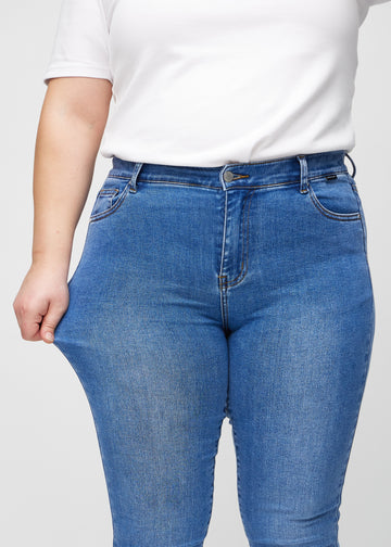 Das Plus-Size-Model zieht die Jeans am Oberschenkel auseinander, um den Stretch zu zeigen.