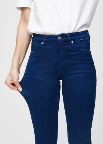 Skinny-Jeans für Damen in Dunkelblau, Farbe Royals. Ein Model zieht am Jeansstoff am Oberschenkel, um den Stretch zu zeigen.