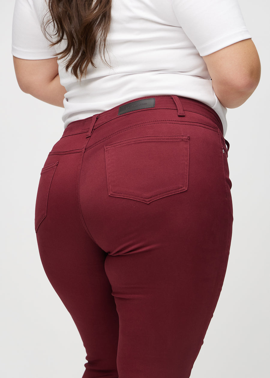 Skinny-Jeans für Damen in Dunkelrot, Farbe Santas. Nahaufnahme der Rückseite an einem Plus-Size-Model, um Details zu zeigen.