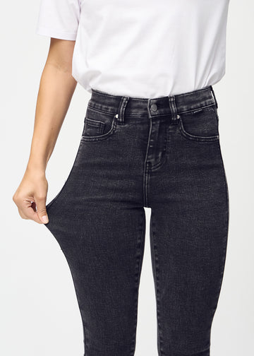 Skinny-Jeans für Damen in Dunkelgrau, Farbe Shadows. Ein Model dehnt den Jeansstoff am Oberschenkel, um den Stretch zu zeigen.