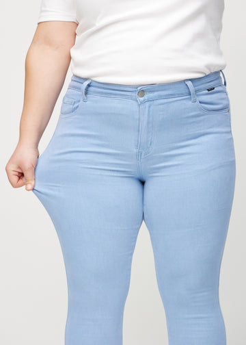 Skinny-Jeans für Damen in Hellblau, Farbe Skies. Ein Plus-Size-Model zieht am Jeansstoff am Oberschenkel, um den Stretch zu zeigen.