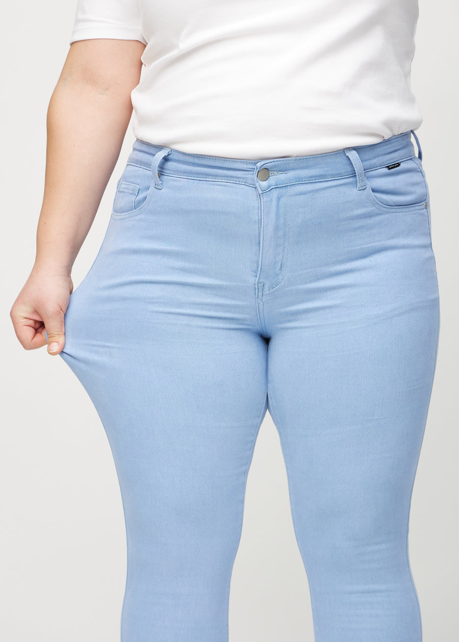 Skinny-Jeans für Damen in Hellblau, Farbe Skies. Ein Plus-Size-Model zieht am Jeansstoff am Oberschenkel, um den Stretch zu zeigen.