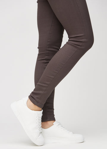 Skinny-Jeans für Damen in Graubraun, Farbe Thunders. Nahaufnahme der eng anliegenden Beinabschlüsse am Knöchel eines Models.