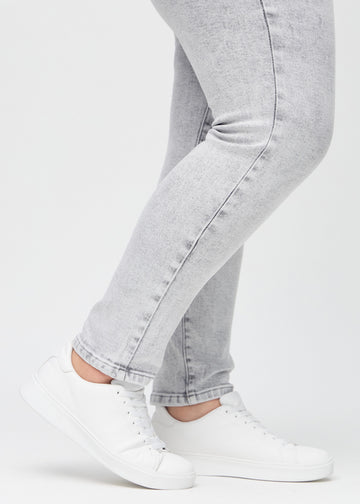 Slim-Jeans für Damen in Hellgrau, Farbe Ashes. Nahaufnahme an den Knöcheln eines Plus-Size-Models, um die Passform am Beinabschluss zu zeigen.