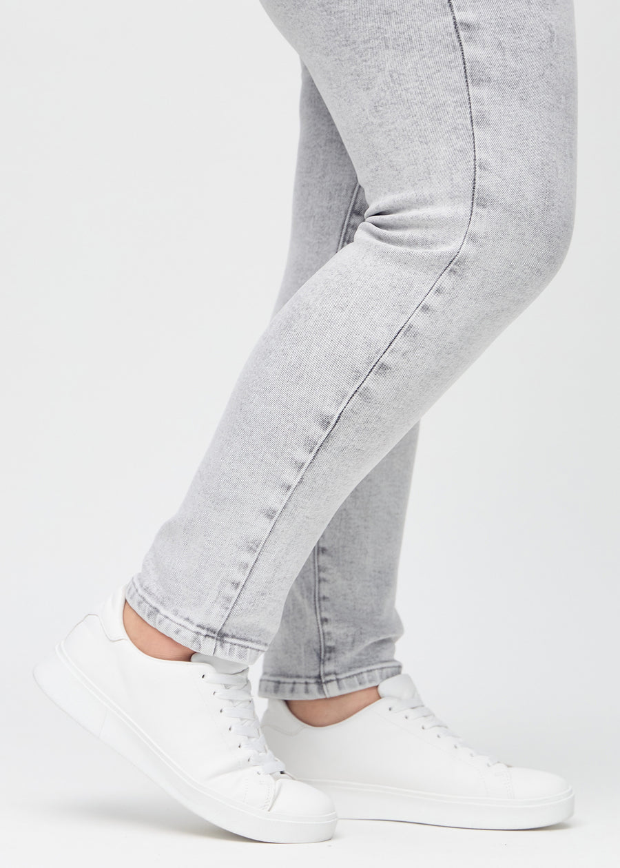 Slim-Jeans für Damen in Hellgrau, Farbe Ashes. Nahaufnahme an den Knöcheln eines Plus-Size-Models, um die Passform am Beinabschluss zu zeigen.