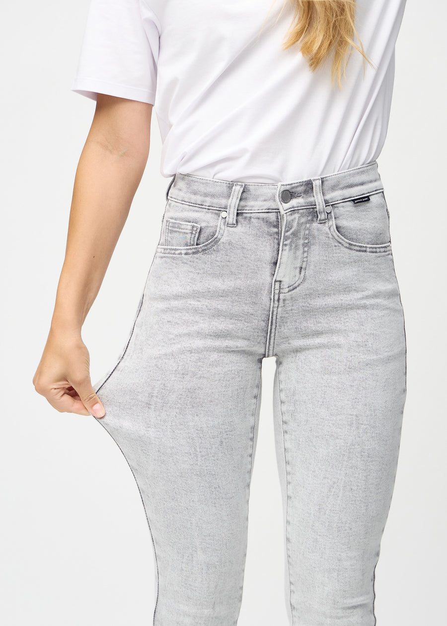 Slim-Jeans für Damen in Hellgrau, Farbe Ashes. Ein Model zieht am Jeansstoff am Oberschenkel, um den Stretch zu zeigen.