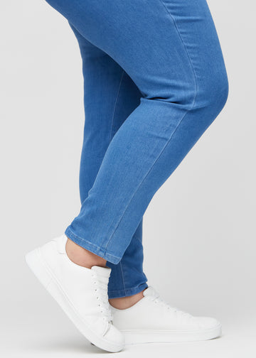 Slim-Jeans für Damen in Blau, Farbe Geraniums. Nahaufnahme an den Knöcheln eines Plus-Size-Models, um die Passform am Beinabschluss zu zeigen.