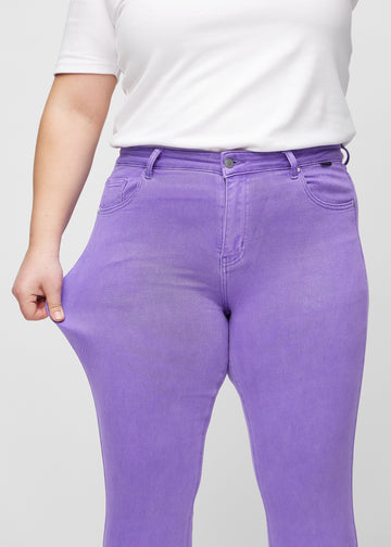 Slim-Jeans für Damen in Lila, Farbe Lavenders. Ein Plus-Size-Model zieht am Jeansstoff am Oberschenkel, um den Stretch zu zeigen.