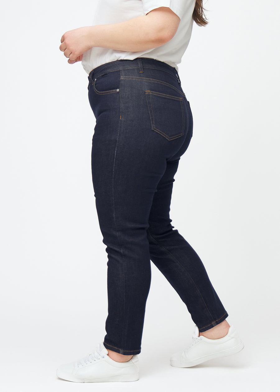 Tief dunkelblaue Denim jeans für Damen in der Farbe Midnights mit slim Passform, von der Seite an einem Plus-Size-Model gesehen.