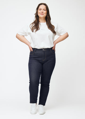 Ganzkörperbild eines Plus-Size-Models in tief dunkelblauer Denim jeans für Damen in der Farbe Midnights mit slim Passform.