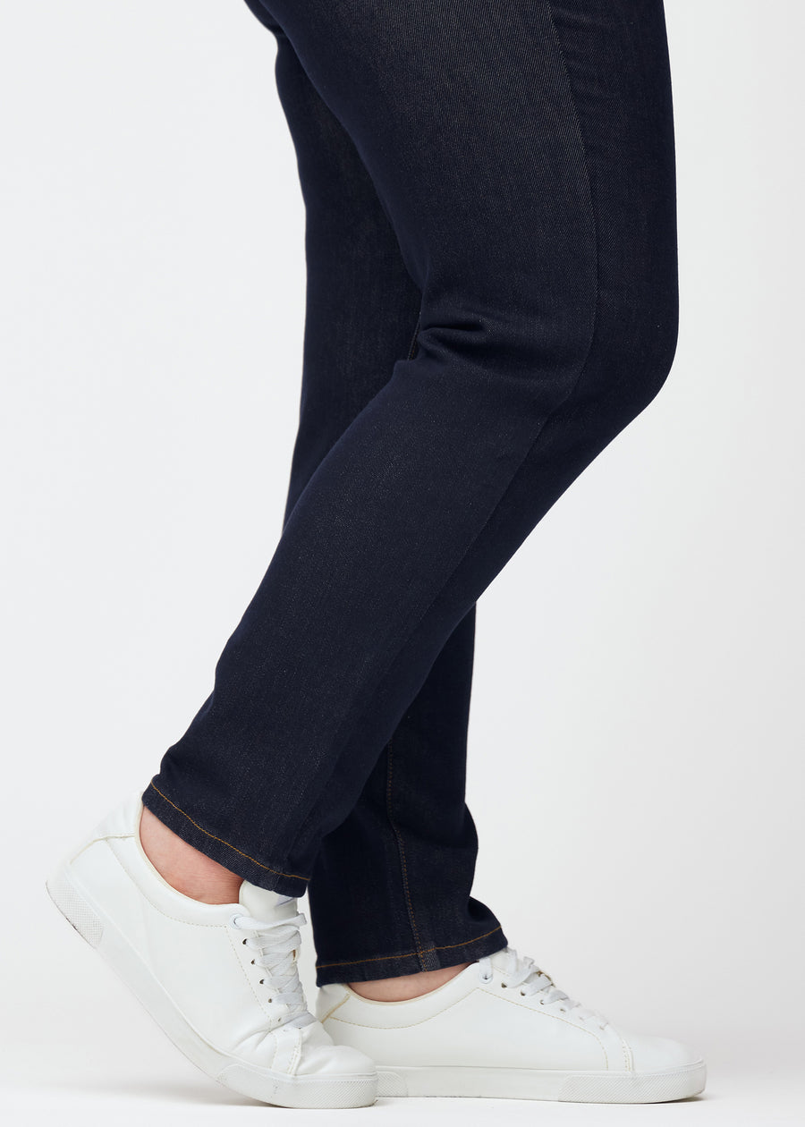 Tief dunkelblaue Denim jeans für Damen in der Farbe Midnights mit slim Passform, in Nahaufnahme an den Knöcheln an einem Plus-Size-Model gesehen, um den figurbetonten Abschluss zu zeigen.