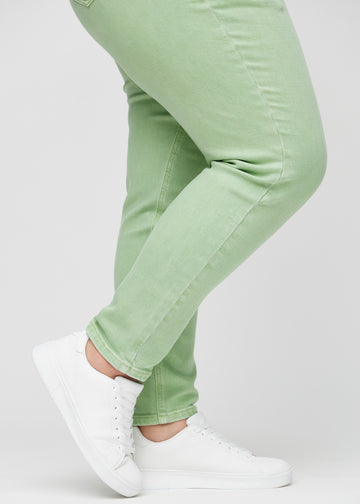 Slim-Jeans für Damen in Hellgrün, Farbe Mints. Nahaufnahme an den Knöcheln eines Plus-Size-Models, um die Passform am Beinabschluss zu zeigen.