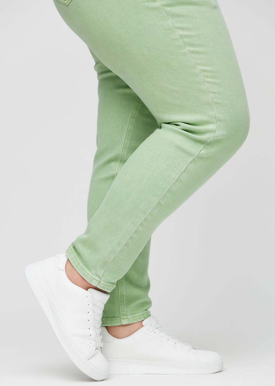 Slim-Jeans für Damen in Hellgrün, Farbe Mints. Nahaufnahme an den Knöcheln eines Plus-Size-Models, um die Passform am Beinabschluss zu zeigen.