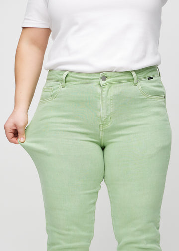 Slim-Jeans für Damen in Hellgrün, Farbe Mints. Ein Plus-Size-Model zieht am Jeansstoff am Oberschenkel, um den Stretch zu zeigen.