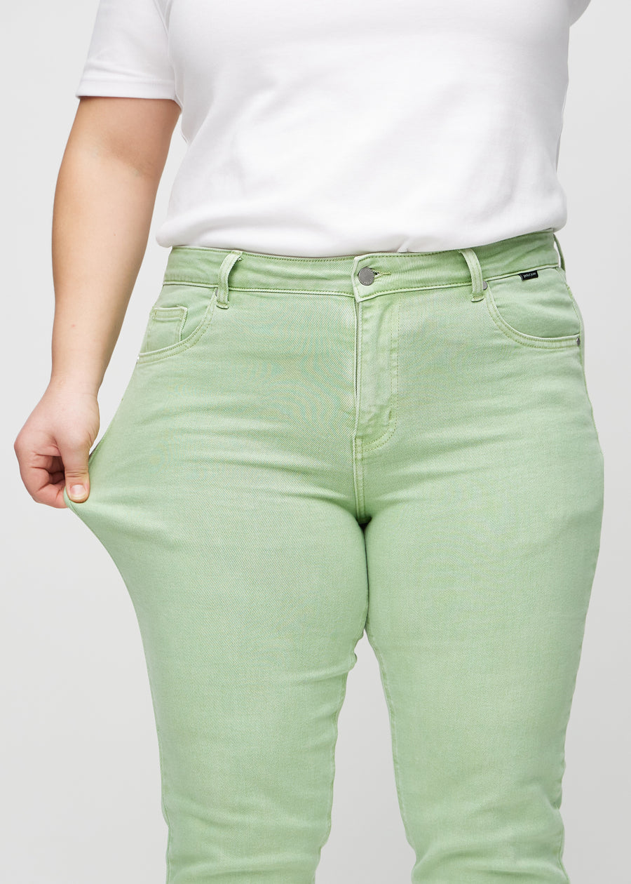 Slim-Jeans für Damen in Hellgrün, Farbe Mints. Ein Plus-Size-Model zieht am Jeansstoff am Oberschenkel, um den Stretch zu zeigen.
